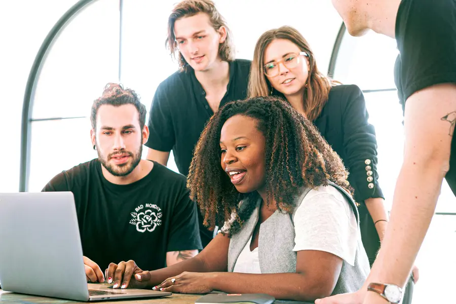 A group of people looking at a laptop together